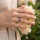 [KI] Silberring mit Karneol an der Hand zwischen Blumen