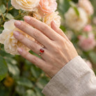 [KI] Silberring mit Karneol an der Hand zwischen Blumen