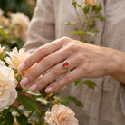 [KI] Silberring mit Karneol an der Hand zwischen Blumen