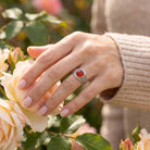 [KI] Silberring mit Karneol an der Hand zwischen Blumen