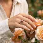 [KI] Silberring mit Karneol an der Hand zwischen Blumen