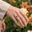 [KI] Silberring mit Karneol an der Hand zwischen Blumen