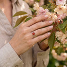 [KI] Silberring mit Karneol an der Hand zwischen Blumen