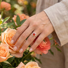 [KI] Silberring mit Karneol an der Hand zwischen Blumen