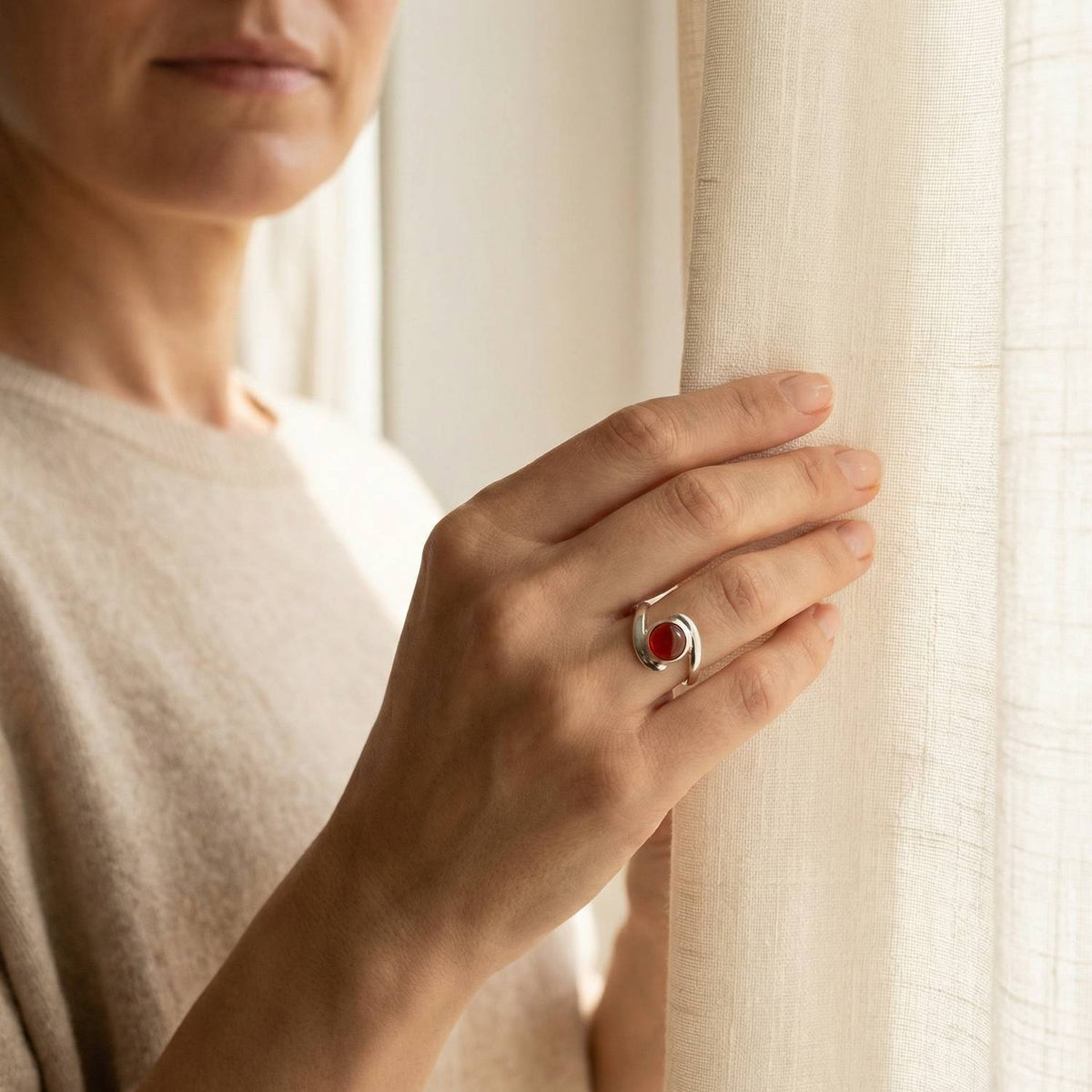 Frau trägt einen Karneolring aus Silber am Fenster