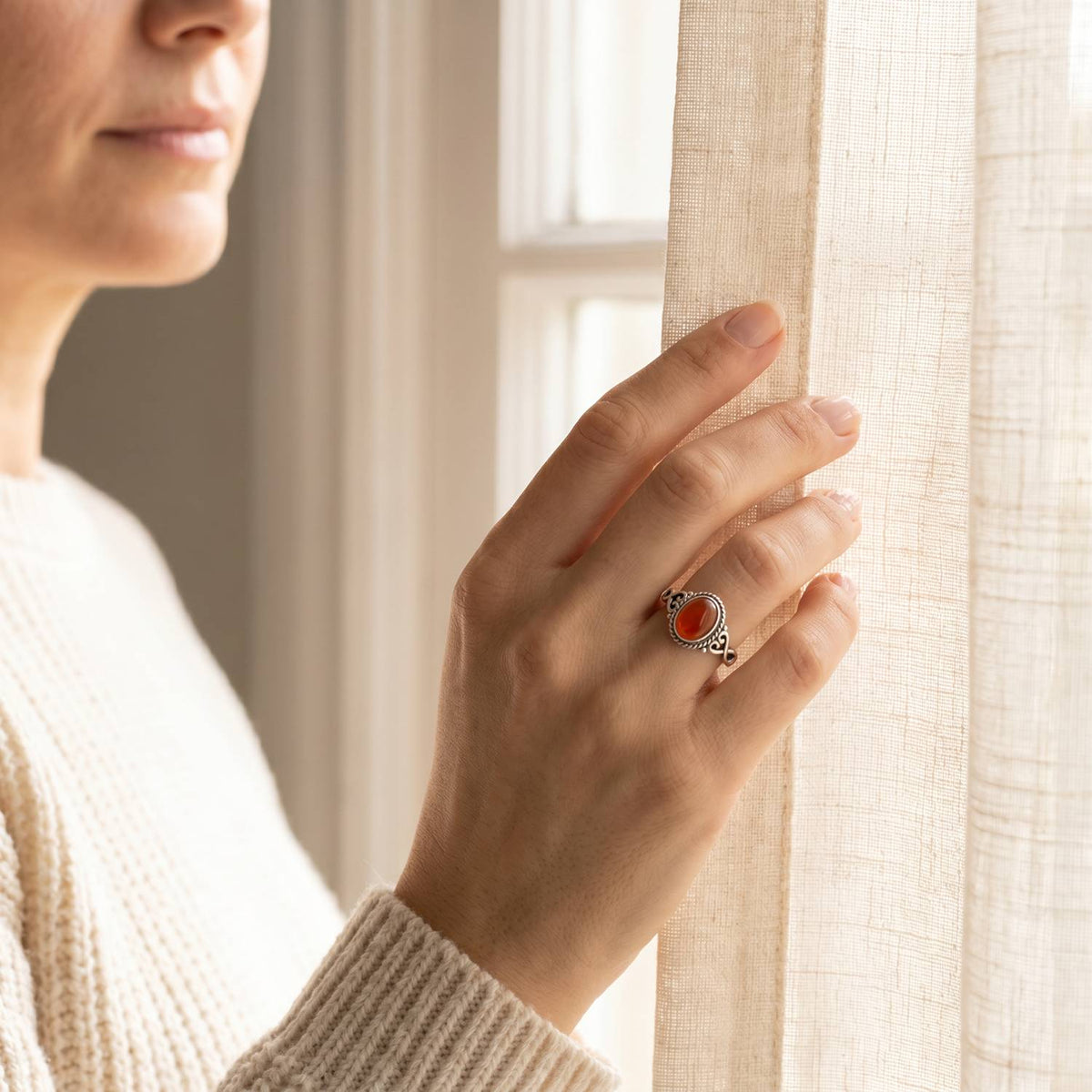 Frau trägt einen Karneolring aus Silber am Fenster