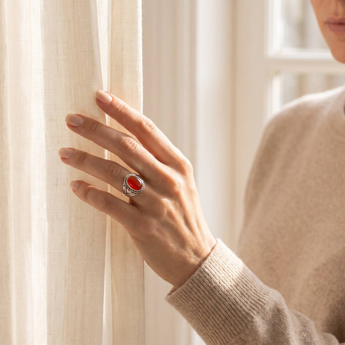 Frau trägt einen Karneolring aus Silber am Fenster