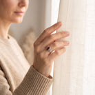 [KI] Frau trägt einen Karneolring aus Silber am Fenster