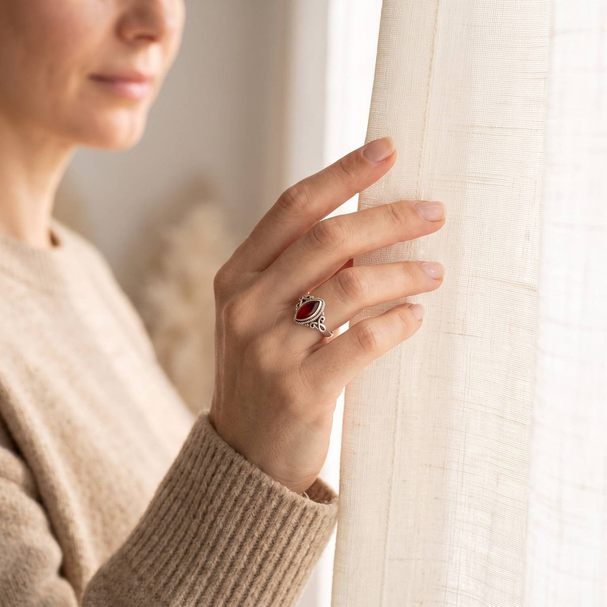 Frau trägt einen Karneolring aus Silber am Fenster