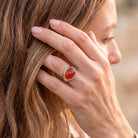 [KI] Frau trägt Silberring mit Karneol an der Hand am Haar