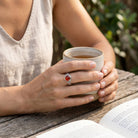 [KI] Karneolring aus Silber getragen beim Lesen mit einer Tasse