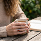[KI] Karneolring aus Silber getragen beim Lesen mit einer Tasse