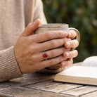 [KI] Karneolring aus Silber getragen beim Lesen mit einer Tasse