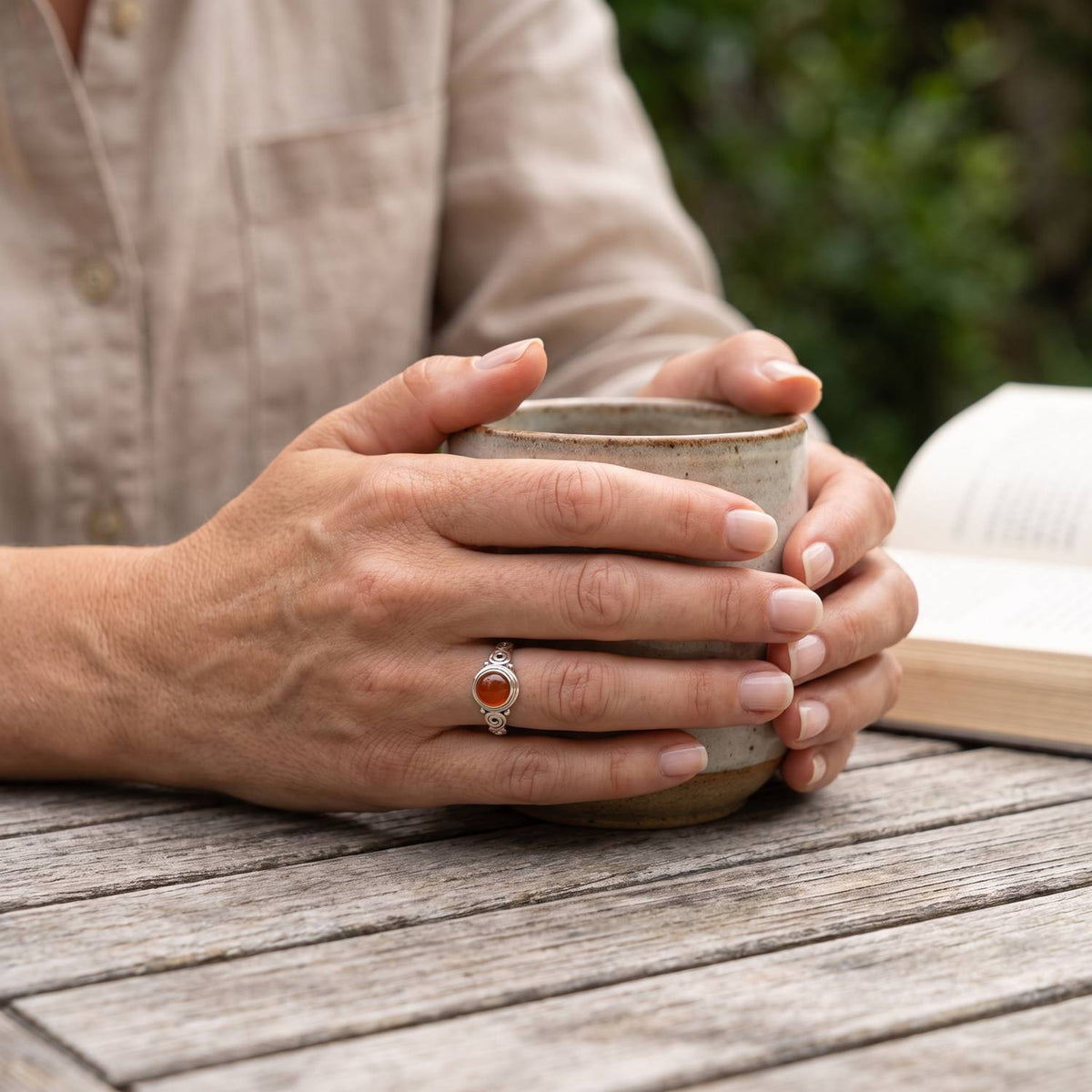 Karneolring aus Silber getragen beim Lesen mit einer Tasse