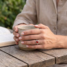 [KI] Karneolring aus Silber getragen beim Lesen mit einer Tasse