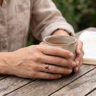[KI] Karneolring aus Silber getragen beim Lesen mit einer Tasse