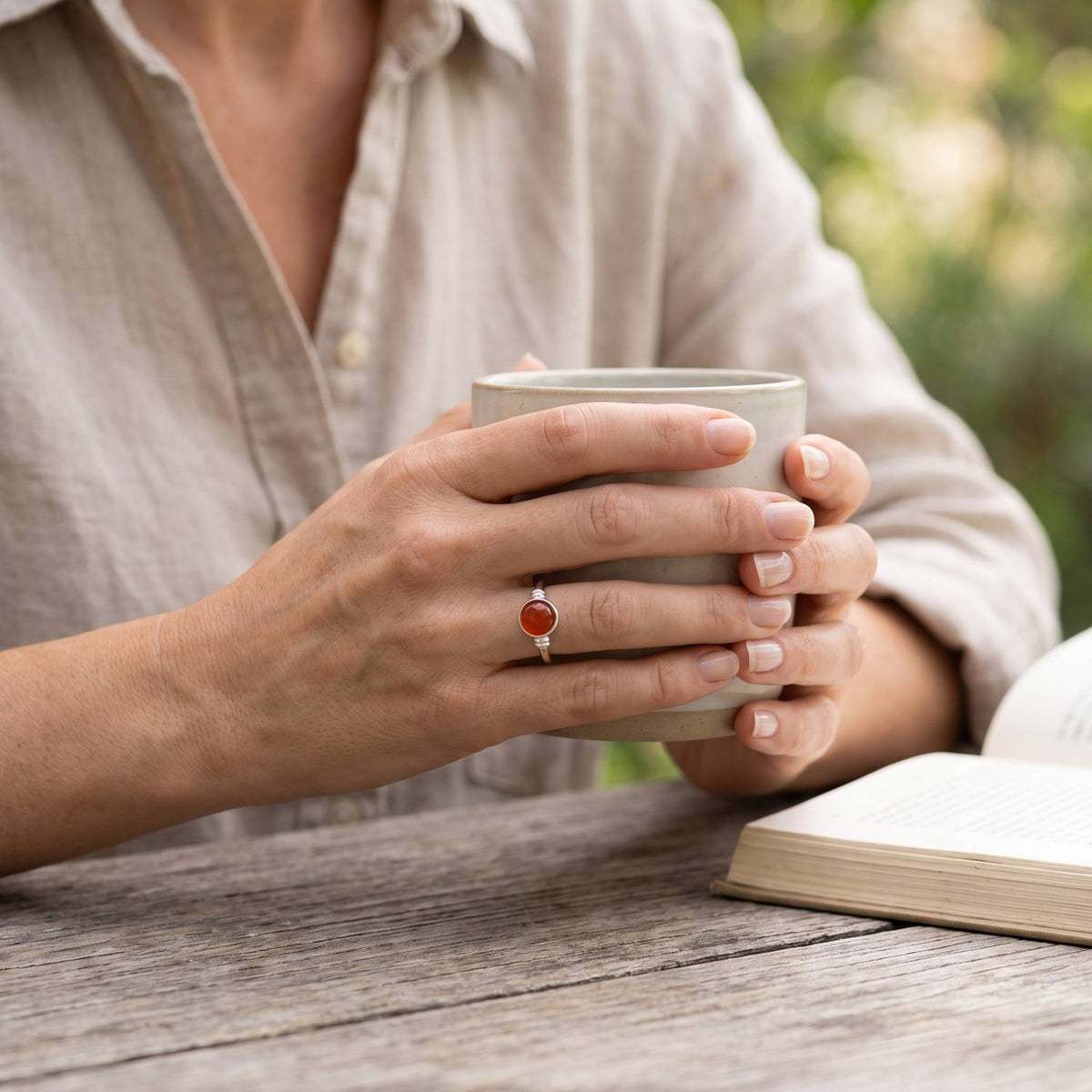 Karneolring aus Silber getragen beim Lesen mit einer Tasse