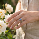[KI] Silberring mit Labradorit an der Hand zwischen Blumen