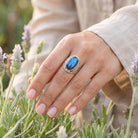 [KI] Silberring mit Labradorit an der Hand zwischen Blumen