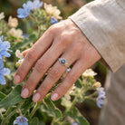 [KI] Silberring mit Labradorit an der Hand zwischen Blumen