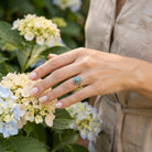 [KI] Silberring mit Labradorit an der Hand zwischen Blumen