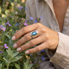[KI] Silberring mit Labradorit an der Hand zwischen Blumen