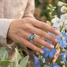 [KI] Silberring mit Labradorit an der Hand zwischen Blumen