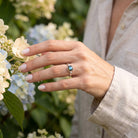[KI] Silberring mit Labradorit an der Hand zwischen Blumen