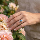 [KI] Silberring mit Labradorit an der Hand zwischen Blumen