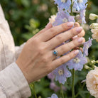 [KI] Silberring mit Labradorit an der Hand zwischen Blumen
