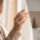[KI] Frau trägt einen Labradoritring aus Silber am Fenster