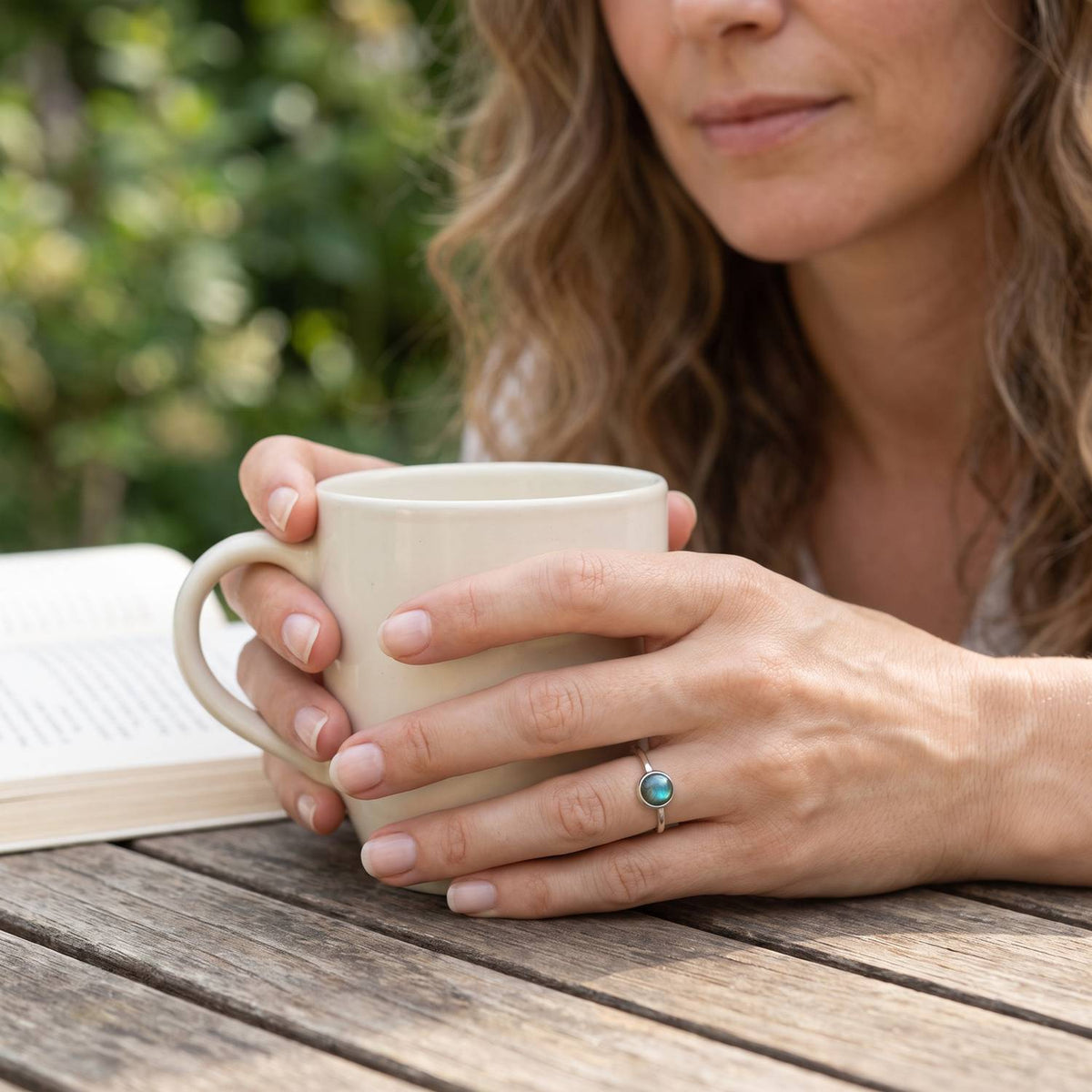 Labradoritring aus Silber getragen beim Lesen mit einer Tasse