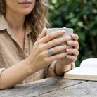 [KI] Labradoritring aus Silber getragen beim Lesen mit einer Tasse