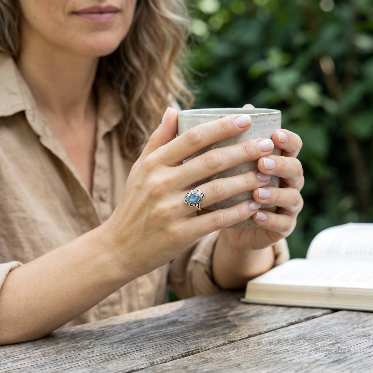 Labradoritring aus Silber getragen beim Lesen mit einer Tasse