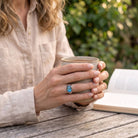 [KI] Labradoritring aus Silber getragen beim Lesen mit einer Tasse