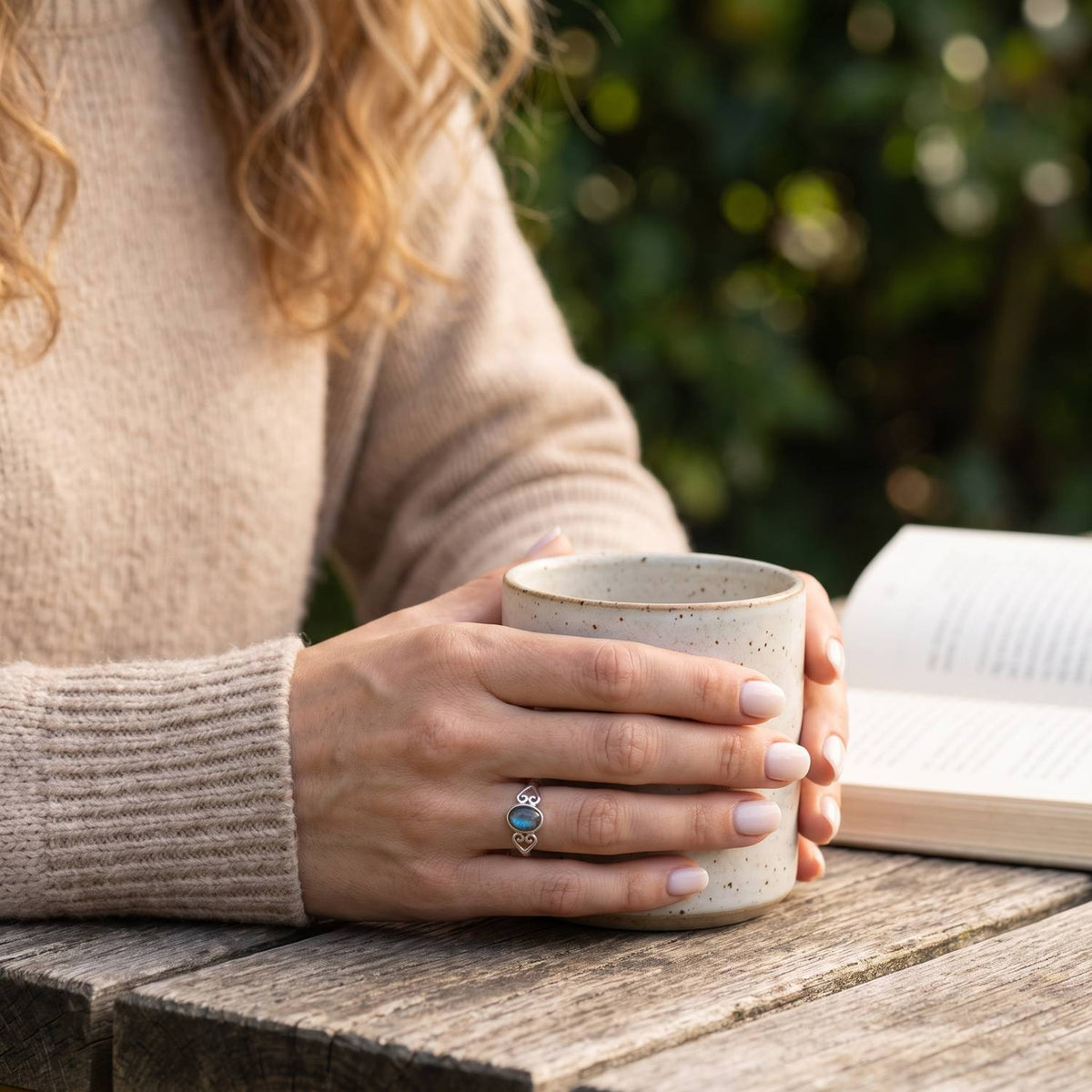 Labradoritring aus Silber getragen beim Lesen mit einer Tasse