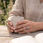 [KI] Labradoritring aus Silber getragen beim Lesen mit einer Tasse