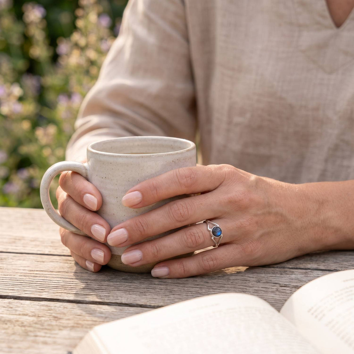 Labradoritring aus Silber getragen beim Lesen mit einer Tasse