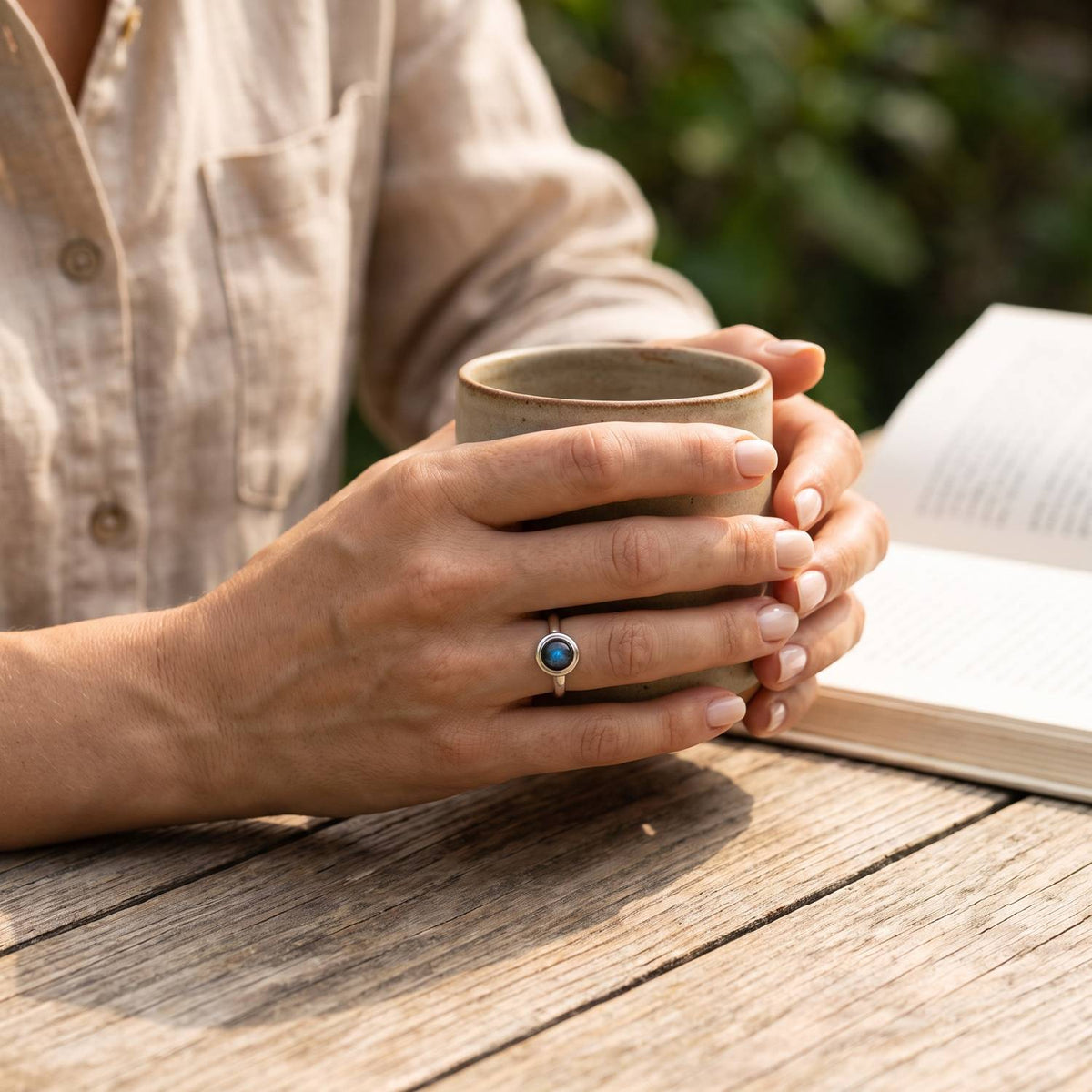 Labradoritring aus Silber getragen beim Lesen mit einer Tasse