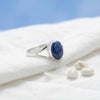 [KI] Silberring mit Lapislazuli auf hellem Stoff