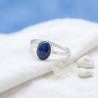 [KI] Silberring mit Lapislazuli auf hellem Stoff