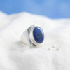 [KI] Silberring mit Lapislazuli auf hellem Stoff