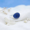 [KI] Silberring mit Lapislazuli auf hellem Stoff