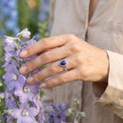 [KI] Silberring mit Lapislazuli an der Hand zwischen Blumen
