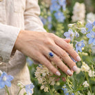 [KI] Silberring mit Lapislazuli an der Hand zwischen Blumen