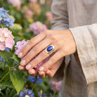 [KI] Silberring mit Lapislazuli an der Hand zwischen Blumen