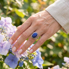 [KI] Silberring mit Lapislazuli an der Hand zwischen Blumen