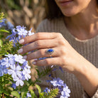 [KI] Silberring mit Lapislazuli an der Hand zwischen Blumen