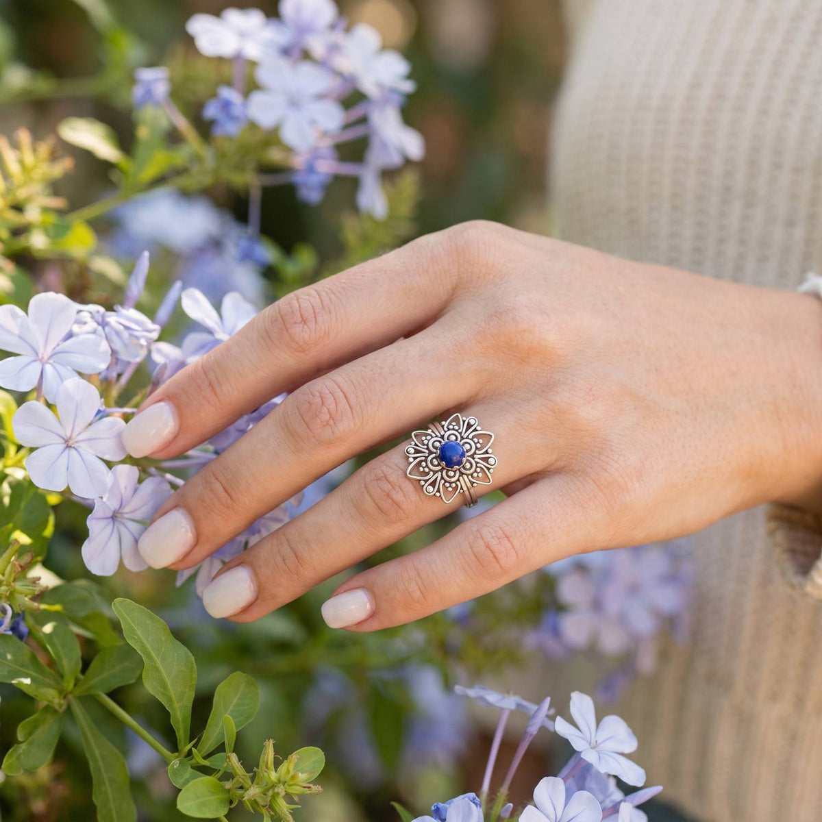Silberring mit Lapislazuli an der Hand zwischen Blumen