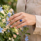 [KI] Silberring mit Lapislazuli an der Hand zwischen Blumen